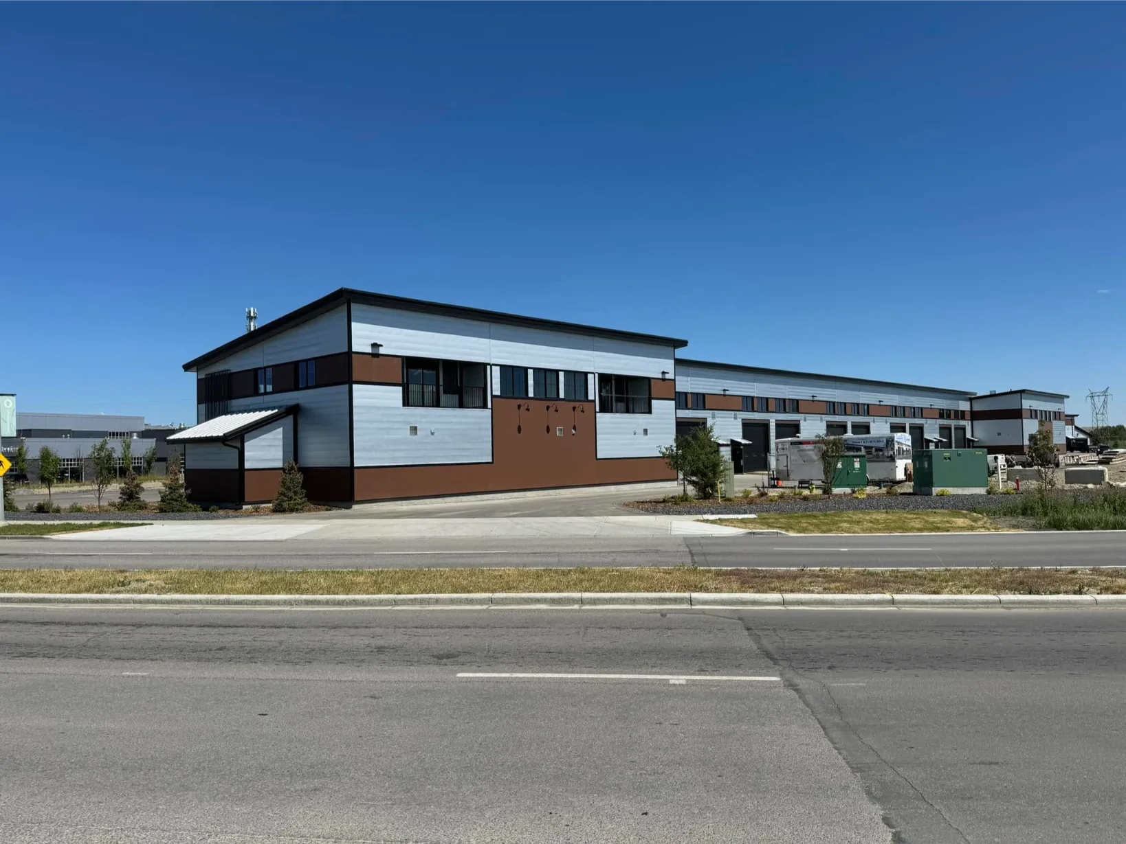 Modern metal buildings stand out against a clear blue sky and open landscape