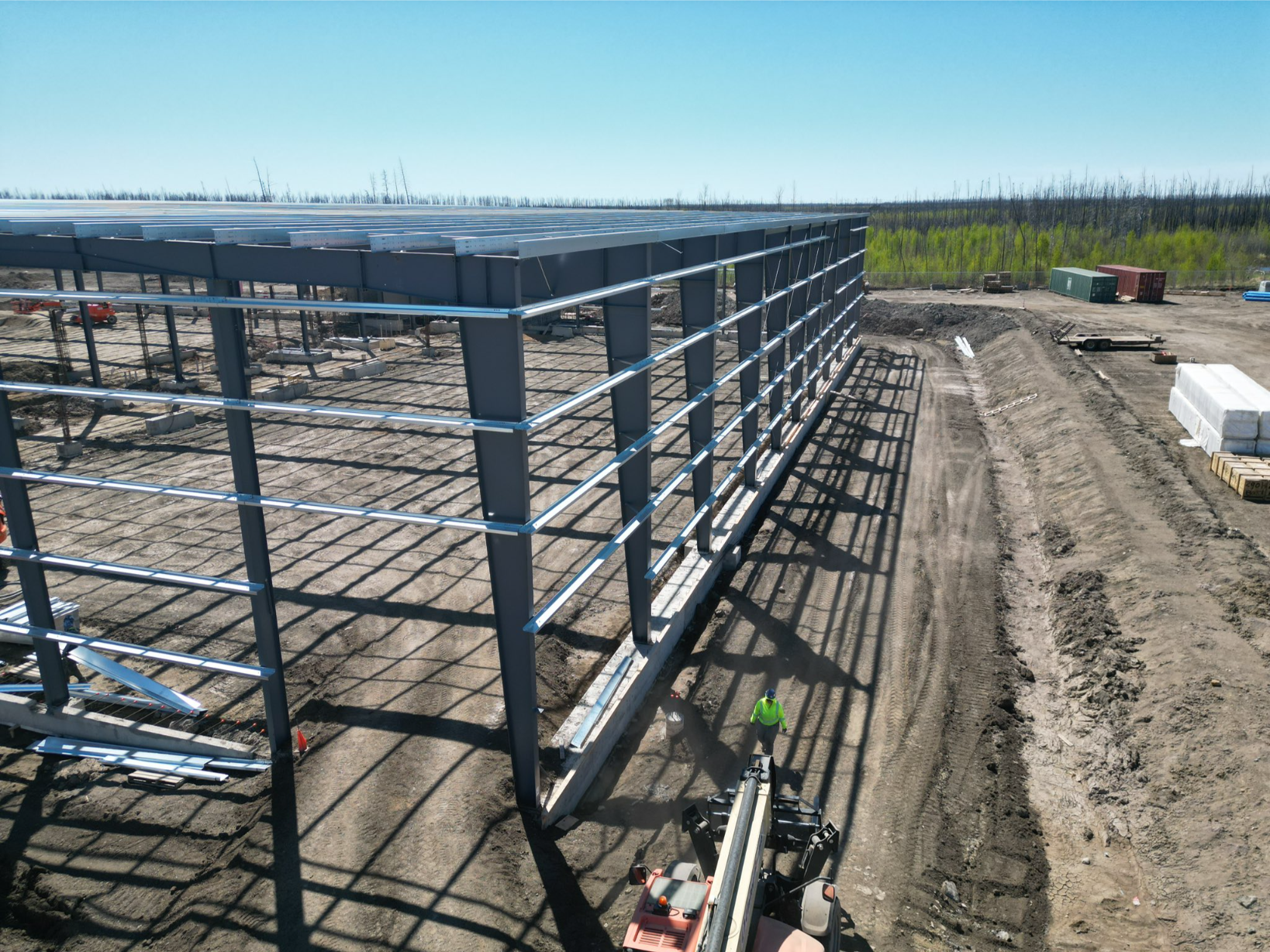 Building installers work on a steel structure under a clear blue sky