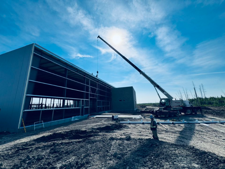Crane lifting materials in a service area at a construction site under clear blue skies