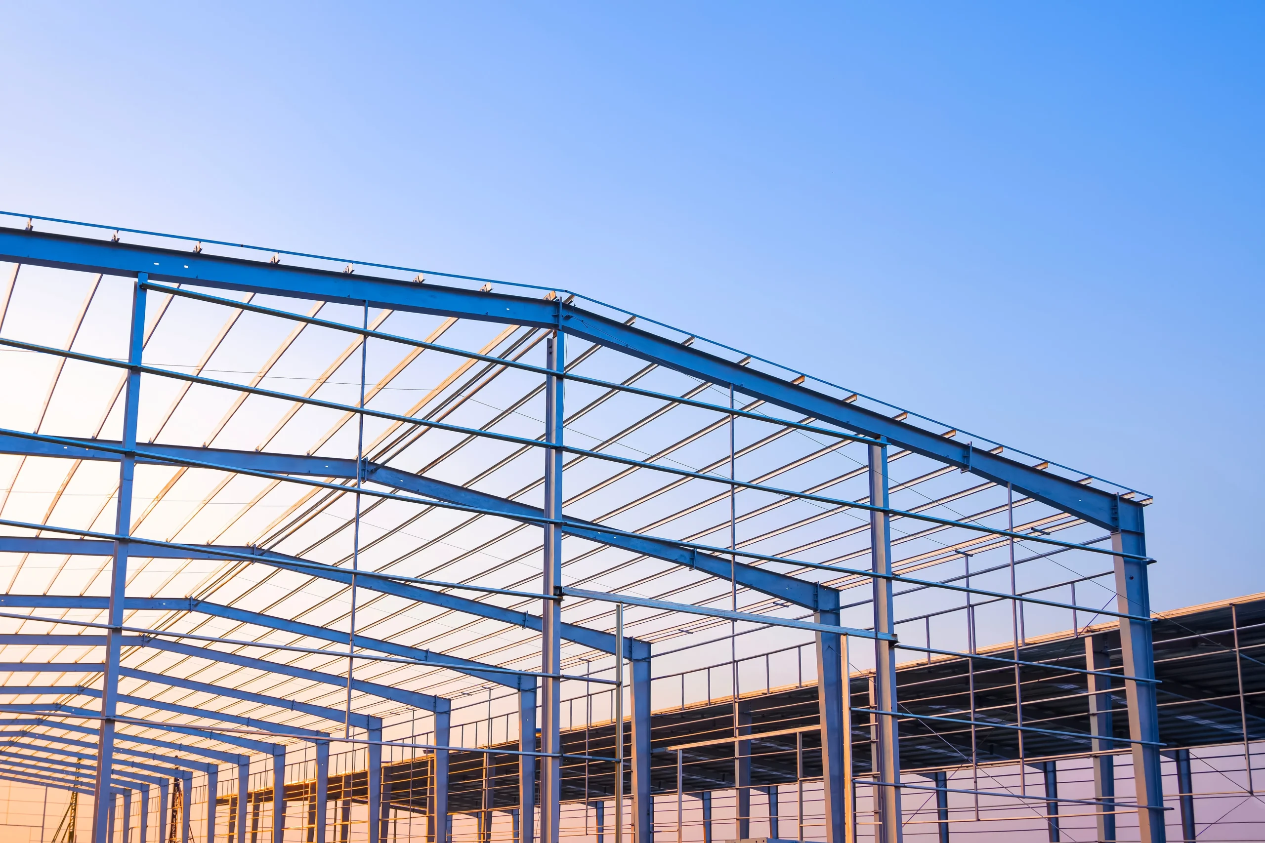 A steel structure frames against a clear blue sky during sunset
