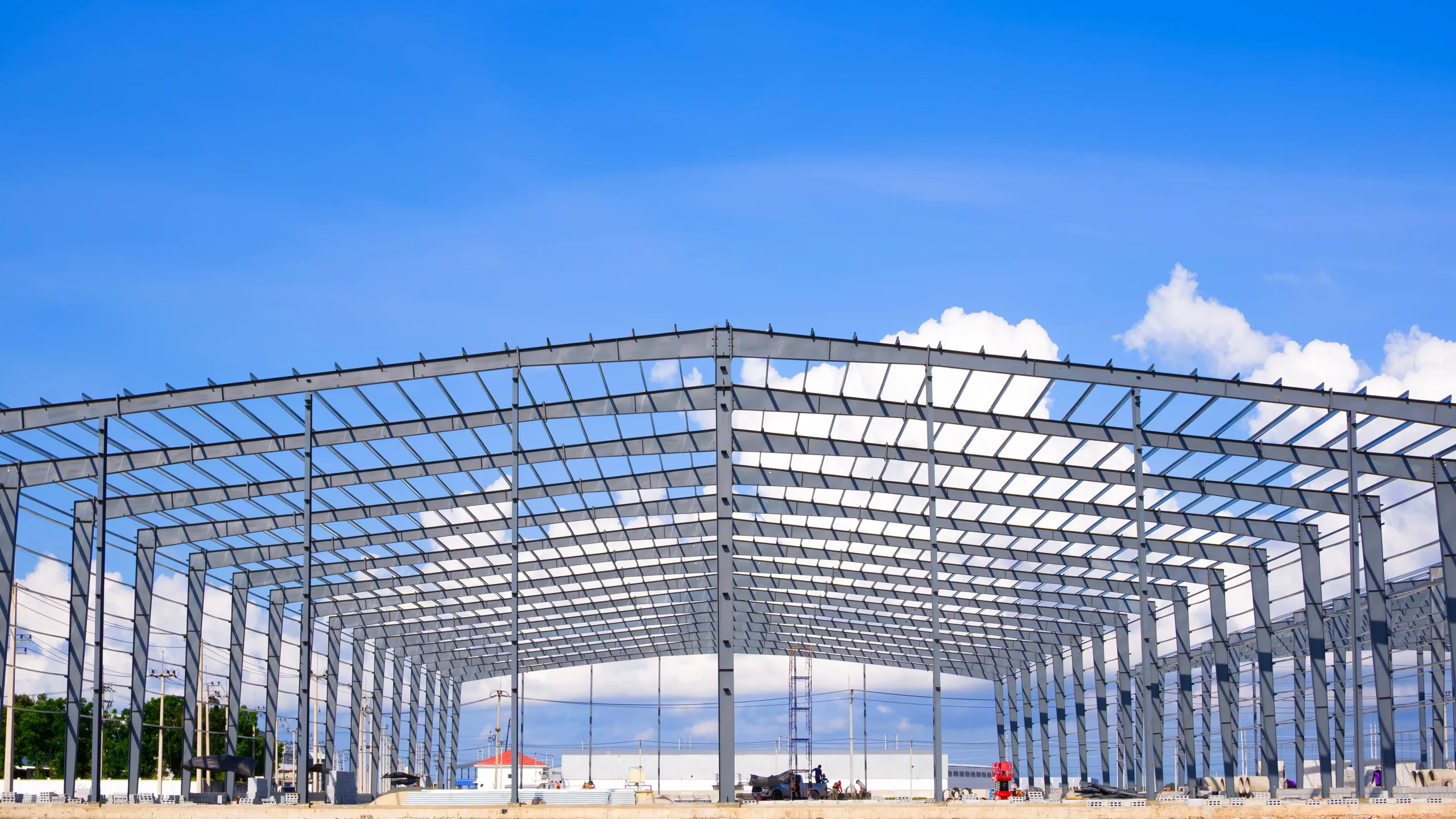 Building envelope construction features a skeletal steel structure against a bright blue sky